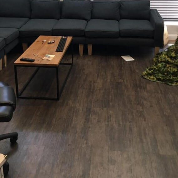 Warm wood‑look luxury vinyl tile flooring in a cosy lounge area, providing a scratch‑resistant, easy‑clean surface ideal for residential or hospitality settings.
